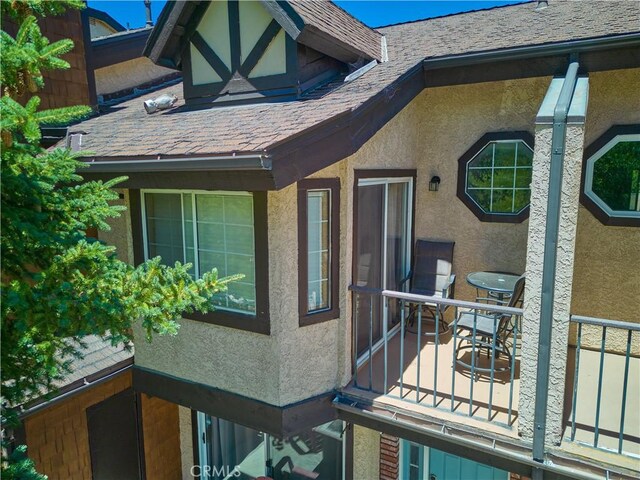 view of side of home with a shingled roof and stucco siding