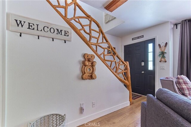 entrance foyer featuring light wood-style floors, stairs, and baseboards