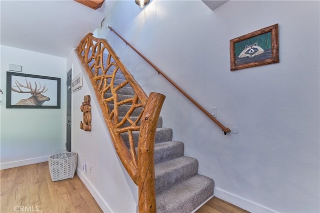 staircase featuring wood finished floors and baseboards