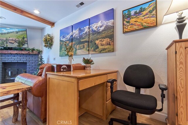 office with recessed lighting, visible vents, a brick fireplace, wood finished floors, and beamed ceiling