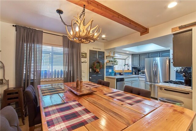 dining space with an inviting chandelier, a barn door, beamed ceiling, and recessed lighting