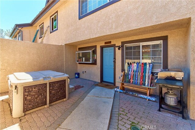 view of exterior entry with a patio area and stucco siding