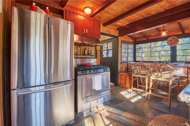 kitchen with wood ceiling, appliances with stainless steel finishes, vaulted ceiling with beams, stone tile flooring, and under cabinet range hood