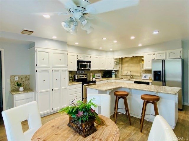 kitchen with a sink, stainless steel appliances, white cabinets, and a center island