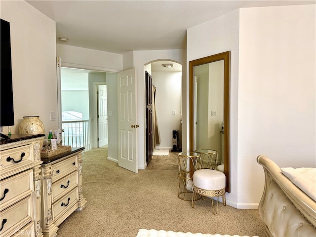 bedroom with baseboards, arched walkways, and light carpet