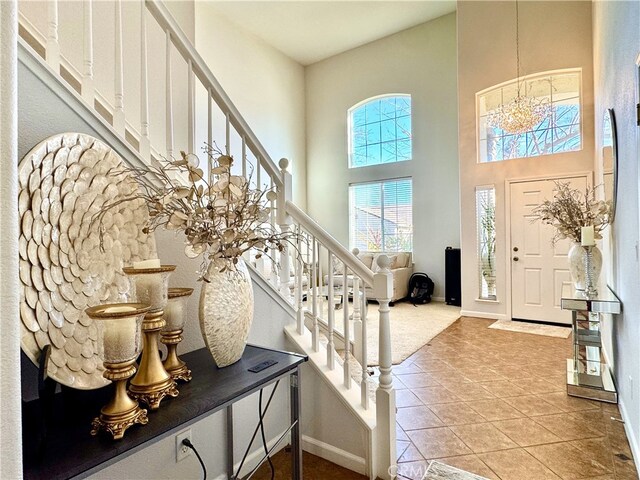 foyer with light tile patterned floors, stairway, a towering ceiling, and baseboards