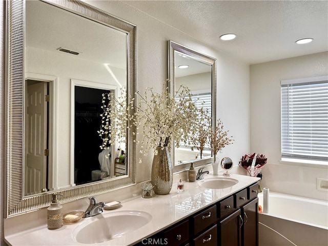 bathroom with a closet, a garden tub, a sink, and double vanity