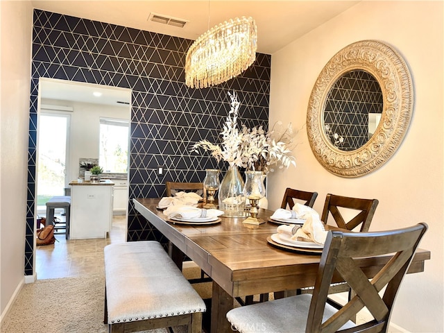 dining room with visible vents, a notable chandelier, tile walls, light tile patterned flooring, and baseboards