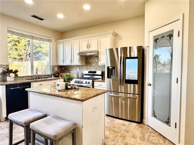 kitchen featuring visible vents, a kitchen island, stainless steel appliances, under cabinet range hood, and backsplash