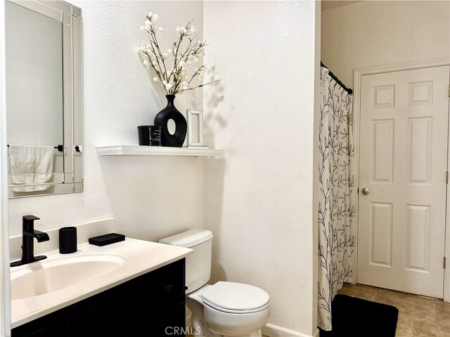 bathroom featuring curtained shower, a textured wall, vanity, and toilet