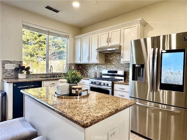 kitchen featuring tasteful backsplash, visible vents, under cabinet range hood, stainless steel appliances, and a sink