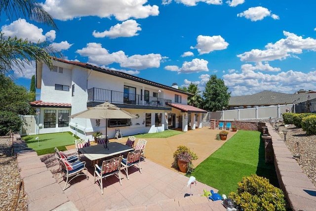 rear view of property with a patio, stucco siding, fence, a balcony, and a tiled roof