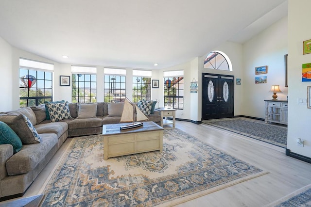 living room featuring lofted ceiling, light wood-style flooring, a wealth of natural light, and baseboards