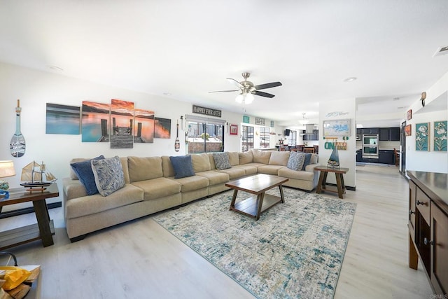 living room with visible vents, ceiling fan, and light wood finished floors