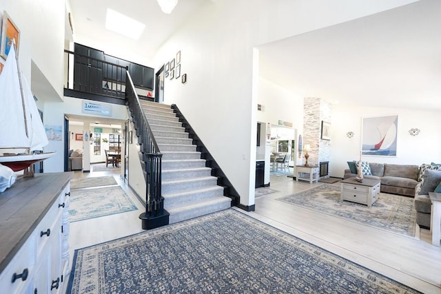 entrance foyer featuring high vaulted ceiling, wood finished floors, and stairs