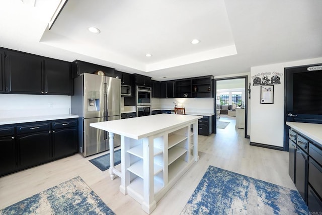 kitchen with open shelves, a tray ceiling, dark cabinetry, and stainless steel appliances