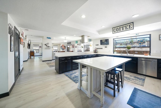 kitchen featuring a peninsula, a wealth of natural light, light countertops, and dishwasher