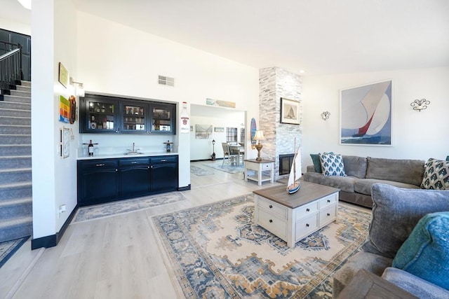 23767 Moonglow Ct, Ramona, CA 92065 - living area featuring a stone fireplace, stairs, light wood-type flooring, wet bar, and visible vents