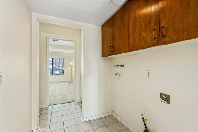 laundry area with cabinet space, light tile patterned floors, baseboards, and electric dryer hookup