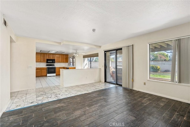 kitchen featuring electric stove, backsplash, brown cabinetry, open floor plan, and black microwave