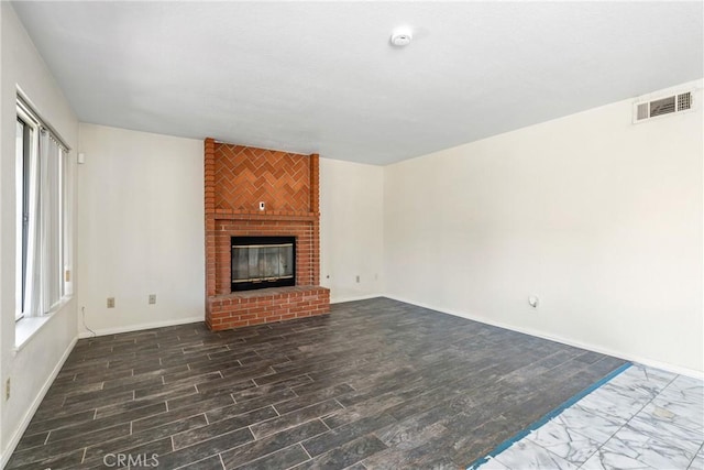 unfurnished living room featuring baseboards, a fireplace, visible vents, and dark wood-type flooring