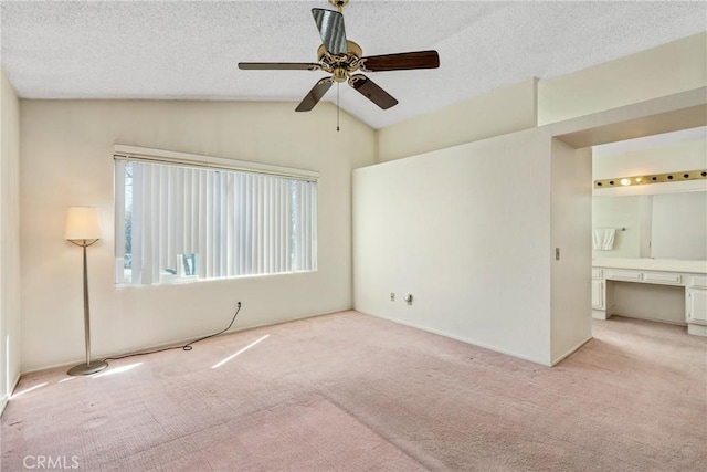 spare room featuring a ceiling fan, lofted ceiling, light carpet, and a textured ceiling