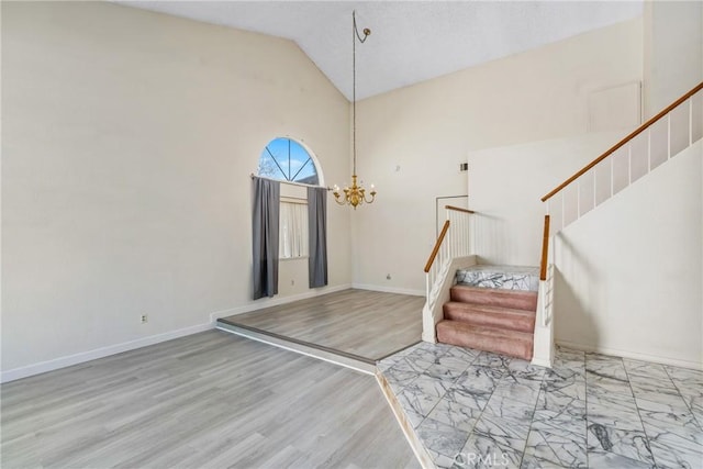 entrance foyer featuring high vaulted ceiling, wood finished floors, baseboards, stairs, and an inviting chandelier