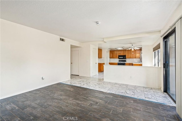 interior space with baseboards, visible vents, light wood-style flooring, ceiling fan, and a textured ceiling