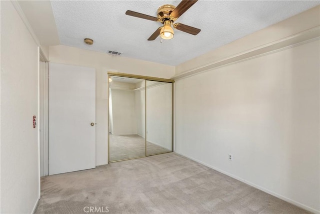 unfurnished bedroom with carpet, a closet, visible vents, and a textured ceiling