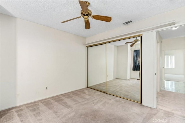 unfurnished bedroom featuring a textured ceiling, carpet floors, a closet, and visible vents