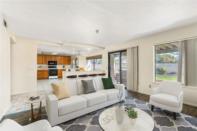 living room with a ceiling fan, baseboards, visible vents, and a textured ceiling