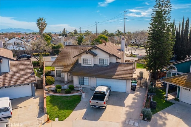 traditional home featuring a garage, driveway, a tile roof, and a gate