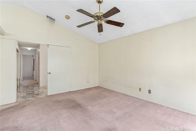 spare room with lofted ceiling, carpet, visible vents, and ceiling fan