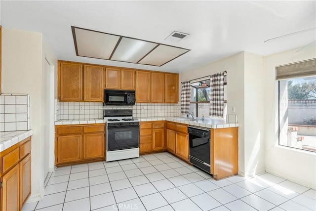 kitchen with tile countertops, black appliances, visible vents, and a wealth of natural light