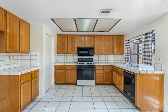 kitchen with visible vents, black appliances, a sink, and tile counters