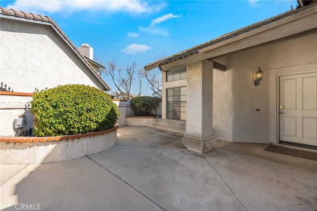 exterior space with a chimney, a patio, fence, and stucco siding