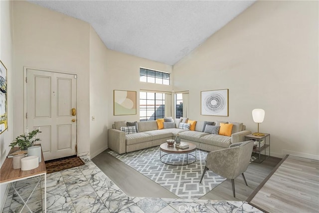 living area featuring high vaulted ceiling, baseboards, and wood finished floors