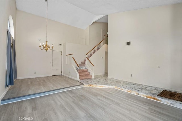 foyer entrance with visible vents, wood finished floors, stairs, high vaulted ceiling, and a notable chandelier