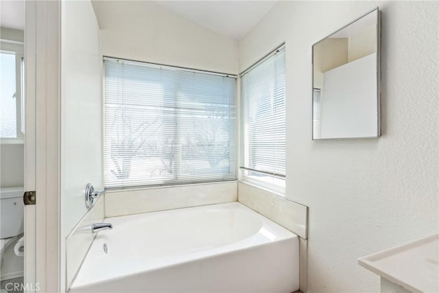 full bathroom with a garden tub and toilet