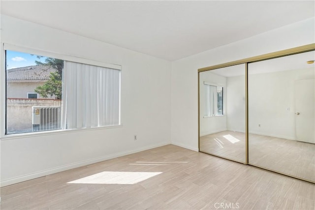 unfurnished bedroom with a closet, baseboards, and wood finished floors