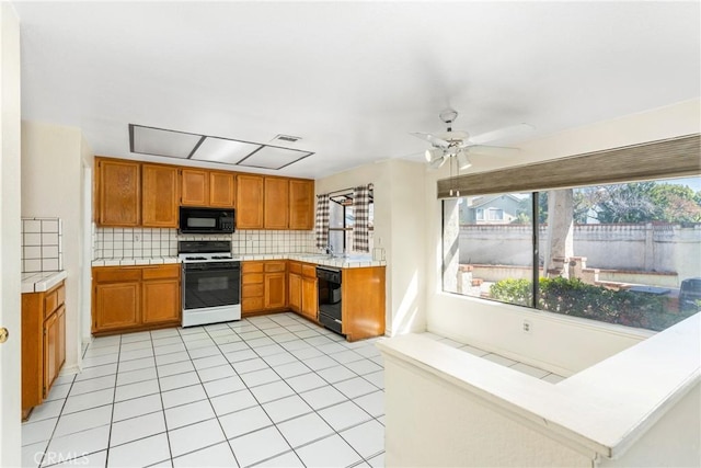 kitchen featuring light tile patterned floors, tasteful backsplash, visible vents, tile countertops, and black appliances