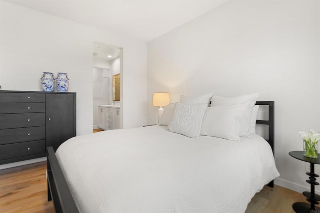 bedroom featuring connected bathroom, baseboards, and wood finished floors