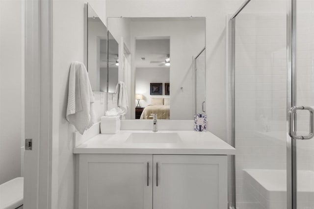 full bath with connected bathroom, a shower stall, toilet, vanity, and a ceiling fan