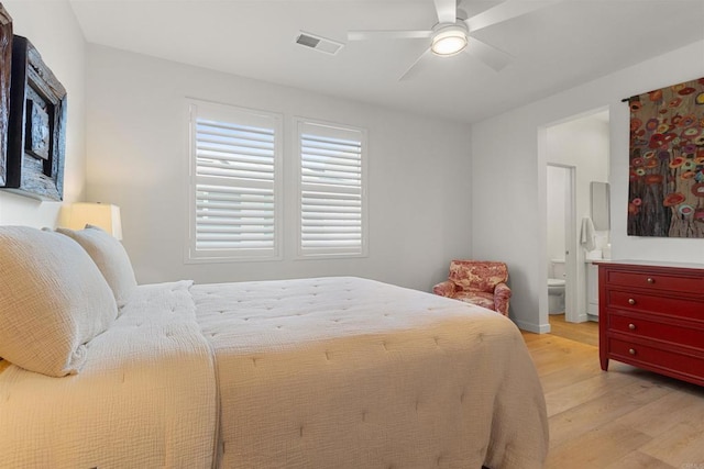 bedroom featuring light wood-style flooring, a ceiling fan, visible vents, and connected bathroom