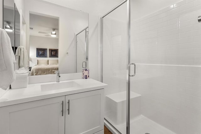 ensuite bathroom with connected bathroom, a ceiling fan, a shower stall, and vanity