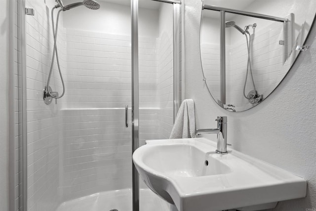 full bath featuring a textured wall, a stall shower, and a sink