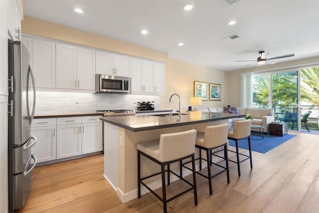 kitchen featuring dark countertops, visible vents, backsplash, appliances with stainless steel finishes, and a sink