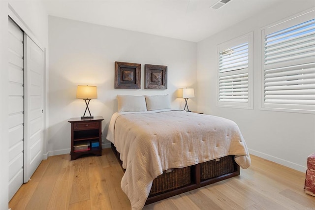 bedroom featuring a closet, visible vents, light wood-type flooring, and baseboards