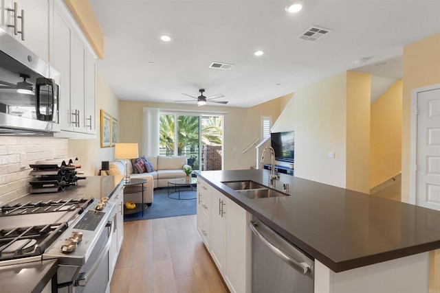 kitchen featuring a sink, stainless steel appliances, dark countertops, and visible vents