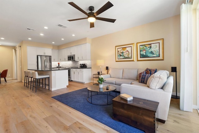 living area with recessed lighting, visible vents, and light wood-style flooring